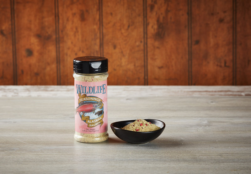 Wildlife Seasonings Alaskan Salmon Seasoning 5.75 oz. bottle beside a small bowl of the seasoning on a rustic wood table