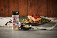 Wildlife Seasonings Alaskan Salmon Seasoning bottle and a bowl of the blend beside a plated salmon fillet with roasted potatoes