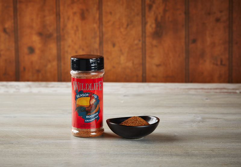 Wildlife Seasonings Rooster Untamed Rub 4.5 oz. bottle beside a small bowl of the rub on a rustic wood table