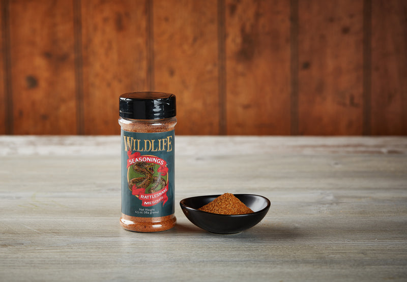 Wildlife Seasonings Rattlesnake Mesquite 6.5 oz. bottle beside a small bowl of the seasoning on a rustic wood table