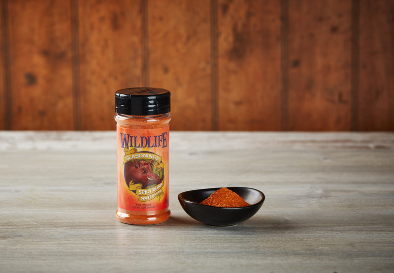 Wildlife Seasonings Spicy Boar Sweet Hot Rub 5.5 oz. bottle beside a small bowl of the rub on a rustic wood table