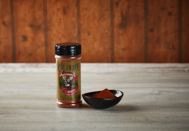 Wildlife Seasonings Deer Chili Seasoning 4.5 oz. bottle beside a small bowl of the seasoning on a rustic wood table