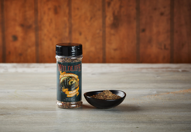 Wildlife Seasonings Bear Rugged Pepper Blend 5.5 oz. bottle beside a small bowl of the seasoning on a rustic wood table